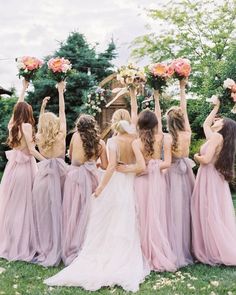 a group of bridesmaids standing in front of each other with their arms up