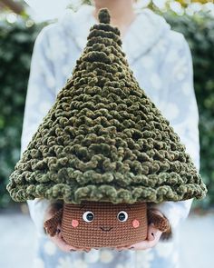 a person holding a crocheted stuffed animal in front of their face and wearing a knitted hat