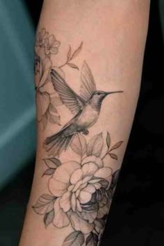 a hummingbird and flowers tattoo on the arm