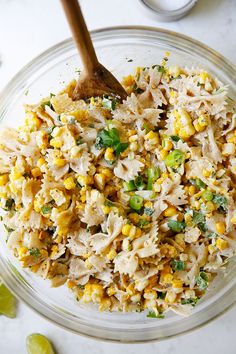 a glass bowl filled with rice and corn next to limes on the side,