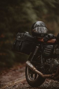 a motorcycle parked on the side of a dirt road in the rain with its luggage strapped to it's back