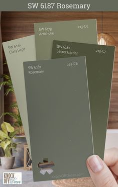 a hand holding three different shades of paint in front of a kitchen counter with the words sw 617 rosemary on it