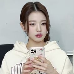 a girl in a white hoodie holding a cell phone