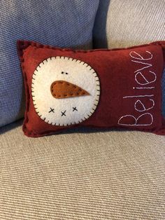 a red pillow with an embroidered bird on it