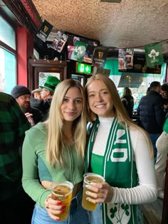 two women standing next to each other holding beers