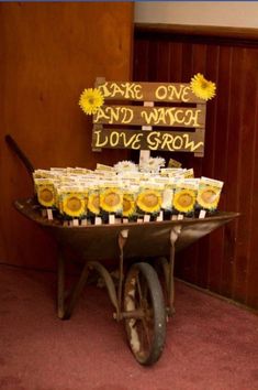 a wheelbarrow filled with sunflowers sitting in front of a sign that says fake one and wagon love grow