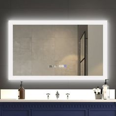 a bathroom vanity with a large mirror above it and lights on the wall behind it