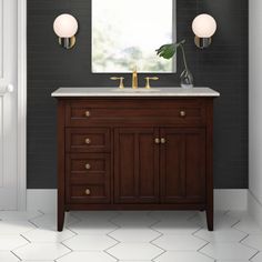 a bathroom vanity with two lights and a mirror on the wall above it, along with a potted plant