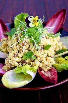 a plate with some food on it and purple flowers in the center, sitting on a wooden table