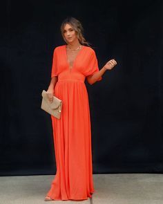 a woman in an orange dress posing for the camera with her hand on her hip