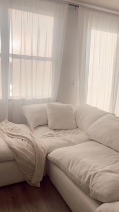 a large white couch sitting next to a window in a living room with wooden floors