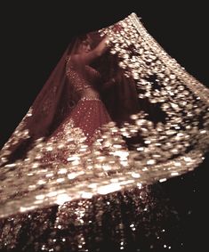 a woman in a red dress is standing under an umbrella that has lights all over it