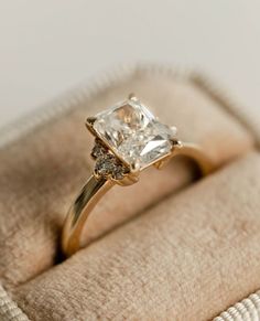 an engagement ring with a princess cut diamond set in yellow gold and diamonds on the band