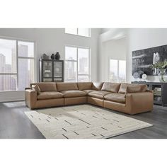 a living room with a sectional couch and large windows in the backround area