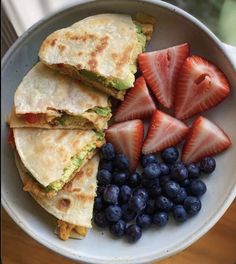 a bowl filled with fruit and quesadillas on top of a table