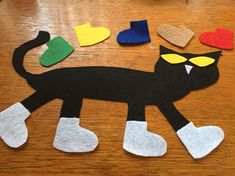 a cat made out of felt sitting on top of a wooden table next to hearts