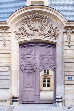 an old building with a large purple door and ornate carvings on the front entrance to it