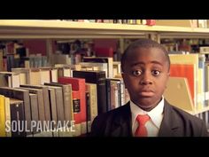 a boy in a suit and tie standing in front of bookshelves with his eyes wide open