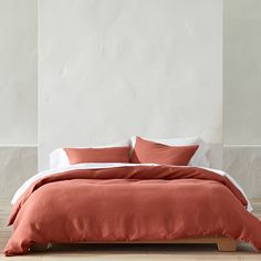 the bed is made up with two pillows and an orange blanket on top of it