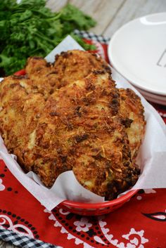 two pieces of fried food in a red bowl on a table with napkins and plates