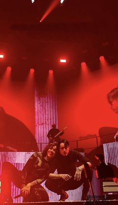 two people on stage with red lighting behind them