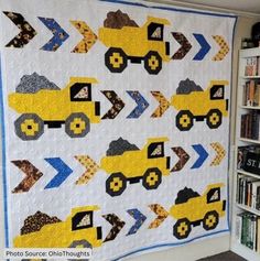 a quilt made to look like a construction truck is hanging on the wall next to bookshelves