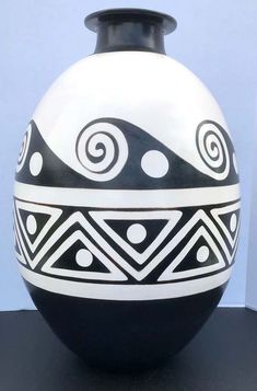 a black and white vase sitting on top of a table next to a blue wall