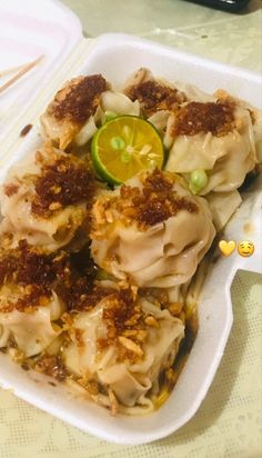 some dumplings are in a white container on a table