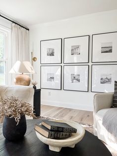 a living room filled with furniture and framed pictures on the wall above a coffee table