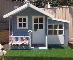 a small blue and white shed with flowers in the window box next to it on green grass