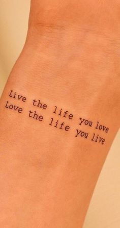 a woman's wrist with the words live the life you love on it