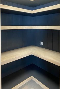 empty shelves in a room with blue walls and wood flooring at the bottom,