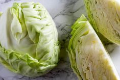 cabbage cut in half sitting on a marble counter top next to another type of vegetable