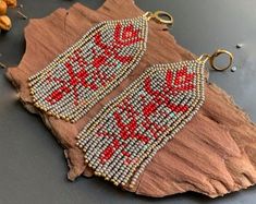 a pair of beaded earrings sitting on top of a piece of wood next to beads