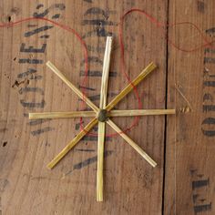 sticks are arranged in the shape of a snowflake on a wooden surface with string