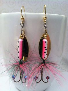 the earrings are decorated with pink and black beads, feathers, and gold hooks on a white cup