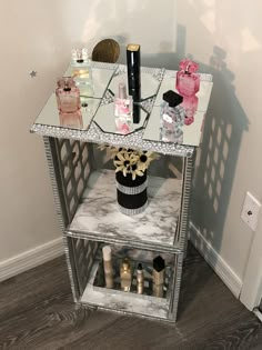 a mirrored shelf with bottles and perfumes on it next to a white wall in a room