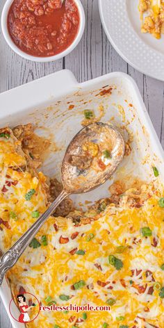 an enchilada casserole in a white dish with a serving spoon