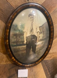 an old photograph of a man in a suit and tie on a wooden wall next to a sign