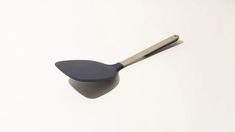 a blue and silver spoon on a white surface with a black handle that is shaped like an egg