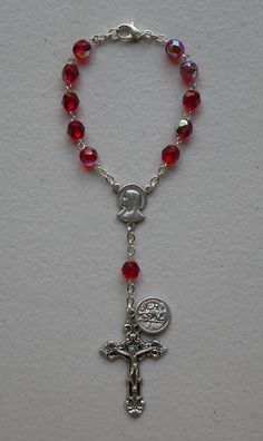 "Precision molded red beads with silver tone metal chain and clasp. SIZE/LENGTH: Total length is 6.75\" including the silver tone Fleur de Lis Crucifix. BEADS: Quality 6 mm beads carefully assembled on a silver tone chain. MEDAL: Saint Christopher Made in Italy Center piece has The Sacred Heart of Jesus and The Immaculate Heart of Mary on the back. The Saint Christopher medal is shown on picture. A Timeless Gift ~ Perfect for any person! This is a very good quality and elegant rosary for use as Red Adjustable Rosary With Round Beads, Adjustable Red Rosary With Round Beads, Adjustable Red Rosary, Red Rosary Beads For Jewelry Making, Adjustable Silver Rosary With Faceted Beads, Adjustable Red Beaded Rosary, Red Beaded Rosary With Round Beads, Silver Rosary With Faceted Beads, Silver Rosary With Faceted Round Beads