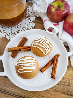 two caramel covered donuts on a white plate next to cinnamon sticks and apples