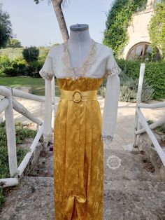 a mannequin wearing a yellow and white dress in front of a wooden fence