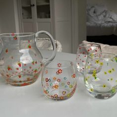 three glass vases sitting on top of a white table next to each other with flowers painted on them