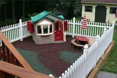 a backyard with a white picket fence and play area