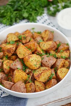 a white bowl filled with potatoes on top of a blue and white table cloth next to some parsley