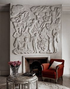 a living room filled with furniture and a large white sculpture on the wall above a fire place