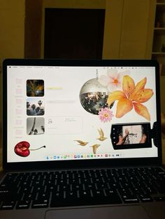 an open laptop computer sitting on top of a wooden table next to a wall with pictures