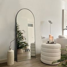 a mirror sitting on top of a wooden floor next to a christmas tree in a living room