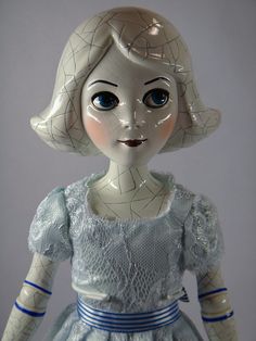 a white doll with blue eyes wearing a dress